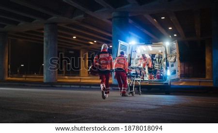 Team of EMS Paramedics React Quick to Provide Medical Help to Injured Patient and Get Him in Ambulance on a Stretcher. Emergency Care Assistants Arrived on the Scene of a Traffic Accident on a Street. Blur