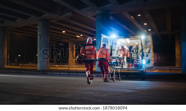 Team of EMS Paramedics React Quick to Provide\
Medical Help to Injured Patient and Get Him in Ambulance on a\
Stretcher. Emergency Care Assistants Arrived on the Scene of a\
Traffic Accident on a Street.\
Blur
