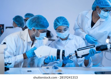 Team of engineer assembling robotic prosthesis part inside biomedical laboratory during innovative medical technology development research project