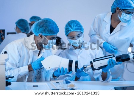 Team of engineer assembling robotic prosthesis part inside biomedical laboratory during innovative medical technology development research project