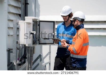 Team engineer inspect electrical control panel using tablet checking voltage, system connection and industrial infrastructure, technician working maintenance and testing circuits, power distribution.
