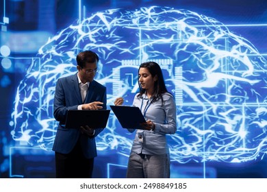 Team of engineers analyzing AI models with large digital brain displayed behind. IT staff members, using machine learning to better understand and develop artificial intelligence