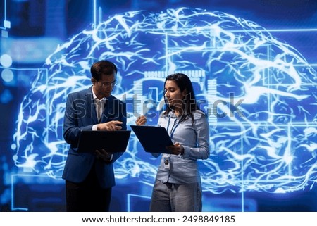 Team of engineers analyzing AI models with large digital brain displayed behind. IT staff members, using machine learning to better understand and develop artificial intelligence