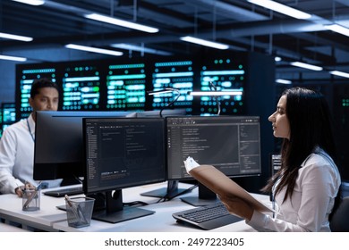 Team of engineers in data center checking emergency procedures documents to ensure system failure prevention. Colleagues in server farm workspace ensuring compliance with industry regulations
