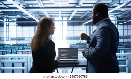 Team of engineers in data center doing brainstorming and running error checking utilities to fix problems. Teamworking colleagues in server hub looking for network issues affecting rigs, camera B