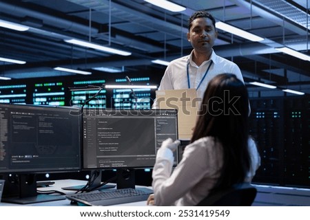 Team of engineers in data center looking for firewall misconfigurations affecting servers. Multiracial workers in server room check systems bottlenecks leading to sluggish data transfer rates