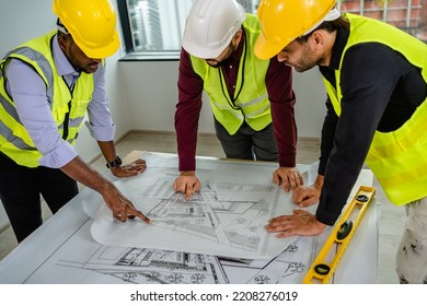 Team of Engineers diverse in safety suite discussing draft blueprints and on the desk at the workplace, architectural projects, Developer real estate, teamwork, architecture, and construction concept. - Powered by Shutterstock