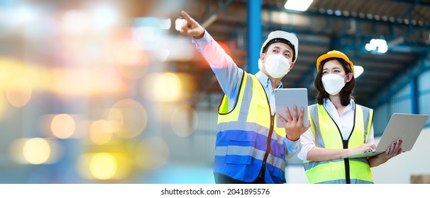 Team engineers and foreman wear a mask, hard hat, and vest. Standing consult discuss industrial production management. Explaining job details through laptops and tablets in factories or warehouses. - Powered by Shutterstock