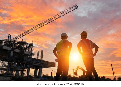 A team of engineers on a construction site pass a blurry construction site at sunset. - Shutterstock ID 2170700189