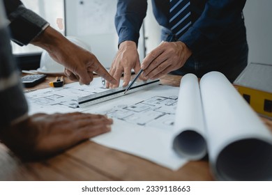 Team of engineers reviewing blueprints Sketch of a new construction project with engineering tools at office desk. For improvement of house designs in mortgage, rent, sale, real estate - Powered by Shutterstock