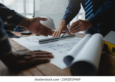 Team of engineers reviewing blueprints Sketch of a new construction project with engineering tools at office desk. For improvement of house designs in mortgage, rent, sale, real estate - Powered by Shutterstock