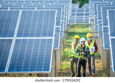 A team of engineers and three Asian architects walked to visit the solar panel. Engineering team wearing medical masks to protect the corona virus (Covid-19). Asian engineers look at solar panels.