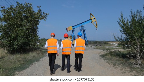 Team of Engineers Worker Men Talking about Petroleum Installations while Walking in Oil Pump Field, Fossil Energy Concept
