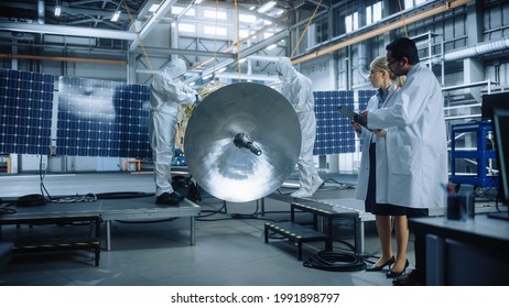 Team Of Engineers Working On Satellite Construction, Use Tablet Computer Talk About Data. Aerospace Spaceship Manufacturing Facility: Team Of Scientists Building Spacecraft For Space Exploration