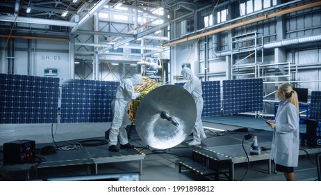 Team Of Engineers Working On Satellite Construction, Use Tablet Computer Talk About Data. Aerospace Spaceship Manufacturing Facility: Team Of Scientists Building Spacecraft For Space Exploration