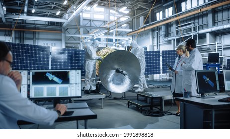 Team Of Engineers Working On Satellite Construction, Use Tablet Computer Talk About Data. Aerospace Spaceship Manufacturing Facility: Team Of Scientists Building Spacecraft For Space Exploration