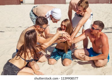 Team of european young beach volley players having rest time after hot won game, sitting in circle on sand, celebrating their victory - Powered by Shutterstock