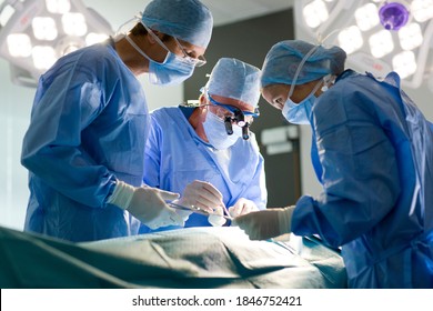 A team of experienced surgeons performing a complex operation with full concentration in well-lit operating room - Shutterstock ID 1846752421