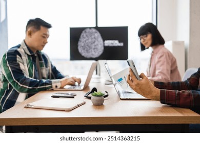 Team of IT experts collaborating on developments of artificial intelligence in office. Professionals working on laptops and mobile devices. Concept of teamwork technology innovation in workplace