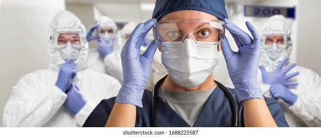 Team of Female and Male Doctors or Nurses Wearing Personal Protective Equiment In Hospital Hallway.