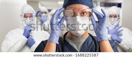 Team of Female and Male Doctors or Nurses Wearing Personal Protective Equiment In Hospital Hallway.