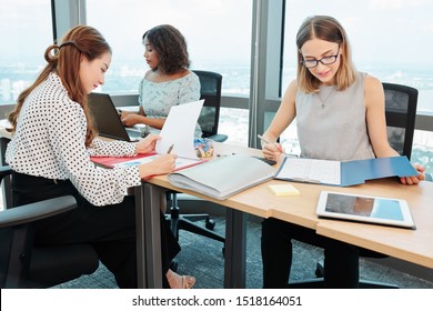 Team of female managers sitting at long office desk and examining documents with financial statistics - Shutterstock ID 1518164051