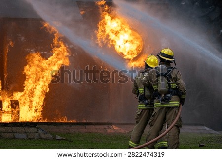 Team of firefighter in fireproof clothe using fog watering hose to put out the burning crashing plane with high flame for fire extinguish risk rescue mission and accident