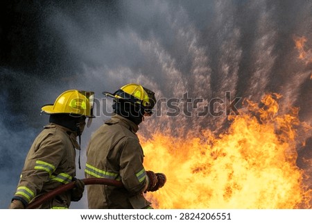 Team of firefighter in fireproof clothe are using twirl fog watering hose to put out the burning building with high flame for fire extinguish risk rescue mission and accident management