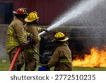 Team of firefighter in fireproof clothes using fog watering hose to put out the burning crashing plane with high flame for fire extinguish risk rescue mission and accident