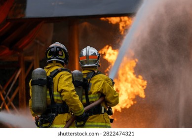 Team of firefighter in fireproof clothes using fog watering hose to put out burning crashing plane with high flame for fire extinguish risk rescue mission and accident