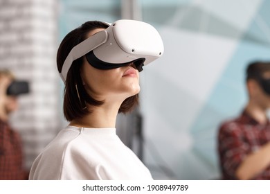 team of four creative engineers working with virtual reality, young woman testing VR glasses or goggles sitting in the office room - Shutterstock ID 1908949789