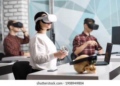 team of four creative engineers working with virtual reality, young woman testing VR glasses or goggles sitting in the office room