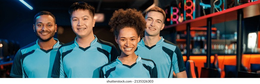 Team of four young multiracial professional cybersport gamers happy with their game while standing in contemporary e-sports club
