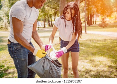 Team Of Friends Cleaning Up The Park By Collecting Litter Into Plastic Bags