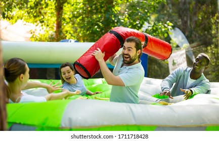 Team Of Friends Playing With Inflatable Sticks On The Trampoline