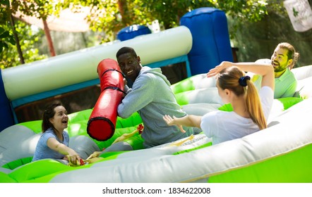 Team Of Friends Playing With Inflatable Sticks On The Trampoline. High Quality Photo