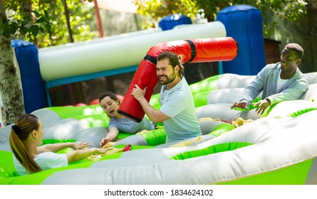 Team Of Friends Playing With Inflatable Sticks On The Trampoline. High Quality Photo