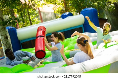 Team Of Friends Playing With Inflatable Sticks On The Trampoline. High Quality Photo