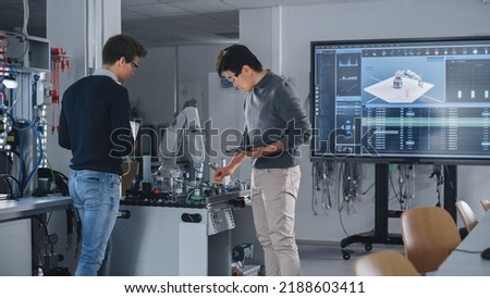 Team of Future Robotics Engineers Working on Robot Arm Design And Discussing Technical Capabilities of Futuristic Device. Students Using Tablet Computers. Digital Technology and Success Concept.