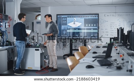 Team of Future Robotics Engineers Working on Robot Arm Design And Discussing Technical Capabilities of Futuristic Device. Students Using Tablet Computers. Digital Technology and Success Concept.