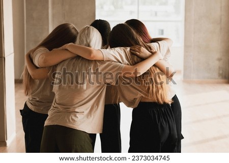 team of girls standing round and hug each other, team spirit and motivation