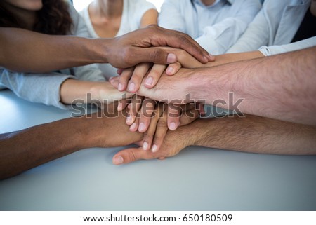 Team of graphic designers forming handstack in office