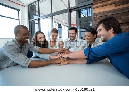 Team of graphic designers forming handstack in office