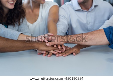 Team of graphic designers forming handstack in office