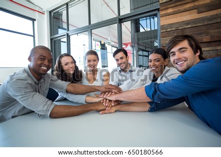 Team of graphic designers forming handstack in office
