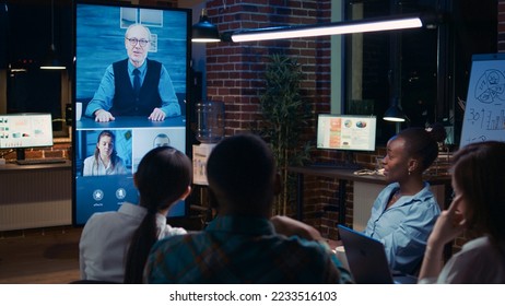 Team greeting executive in videoconference using videocall application, waving hi, company strategy discussion in teleconference. Diverse office workers chatting in business meeting online
