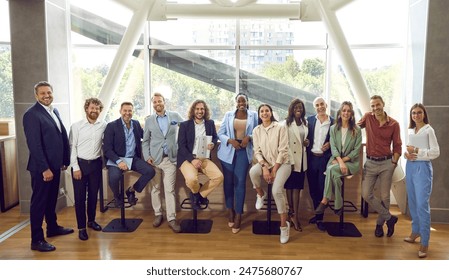 Team of happy diverse people meeting at professional business event. Group portrait smiling young senior multiethnic men and women in smart casual wear in modern office interior with big glass window - Powered by Shutterstock