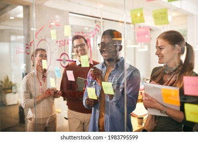 team of happy freelancers brainstorming in front of mind map o glass wall during business project in the office. Focus is on African American man. The view is through the glass. - Powered by Shutterstock