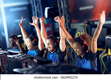 Team of happy professional cyber sport gamers celebrating success while participating in eSports tournament, playing online video games - Shutterstock ID 1824901274