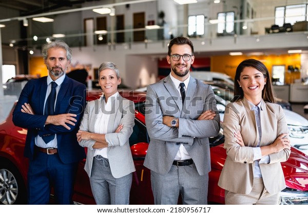 Team of happy salespeople are working\
together at car\
dealership.